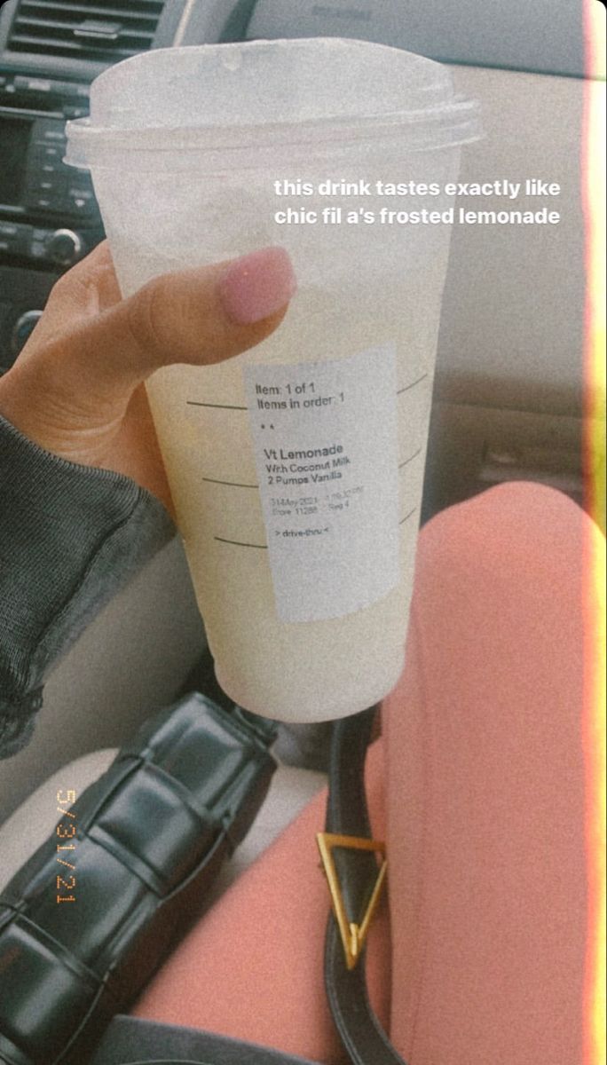 a person holding up a drink in their car