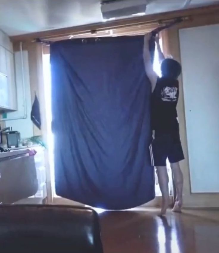 a young boy standing on top of a wooden floor in front of a blue curtain