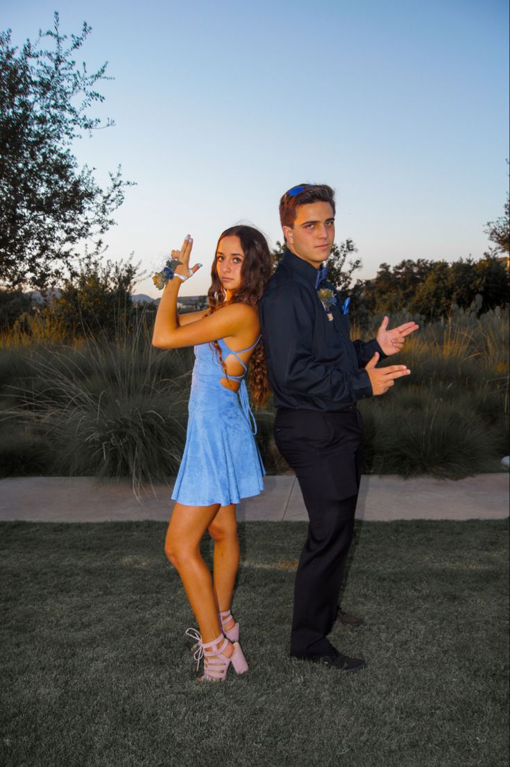 a man and woman posing for a photo in front of the camera with their arms outstretched