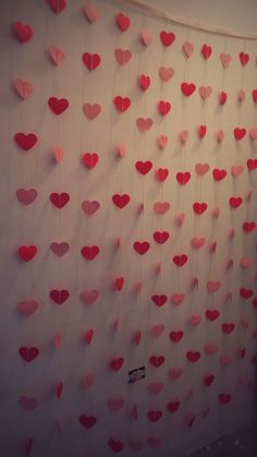 red hearts are hung on the wall next to a white curtain with pink polka dots