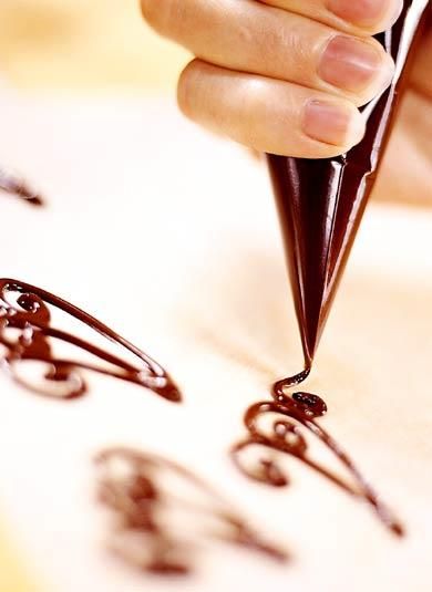 a person is holding a pen and writing something on a piece of paper with chocolate icing