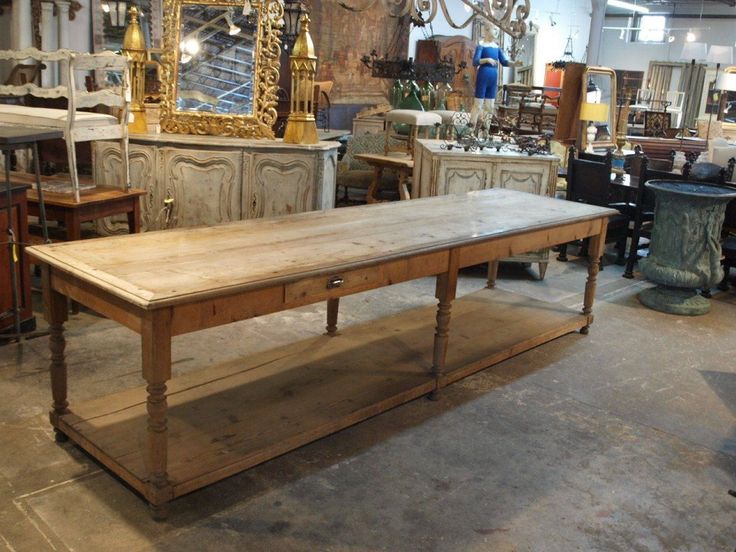 an old wooden table in a room with antique furniture and mirrors on the wall behind it