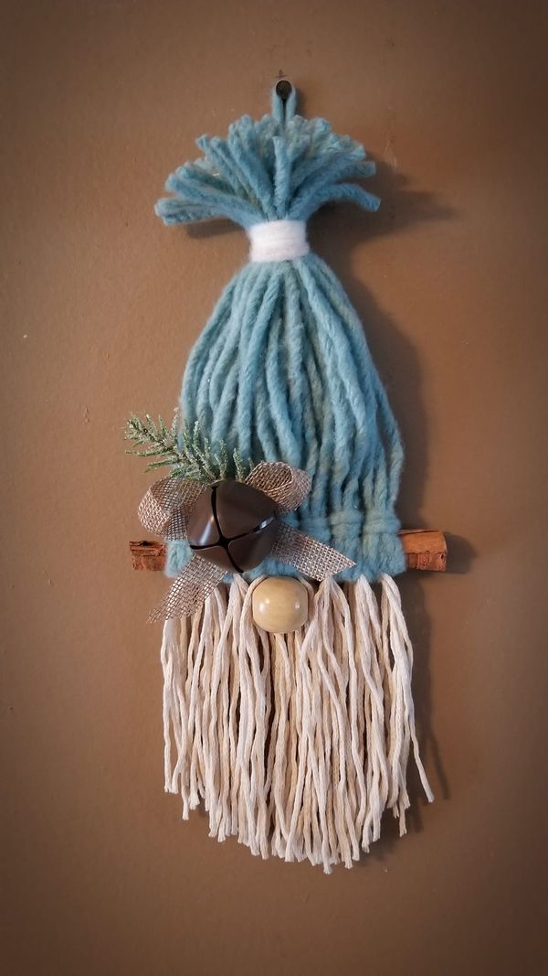 a wall hanging made to look like a bag with fringes and bells on it