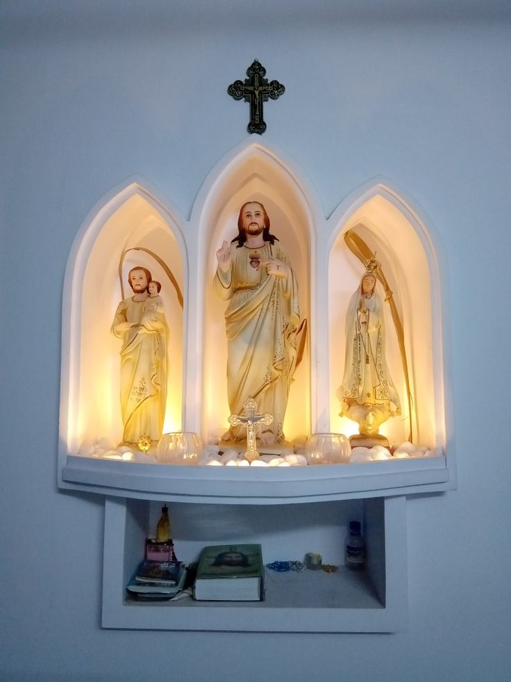 three statues of jesus and mary are on display in the corner of a room with white walls