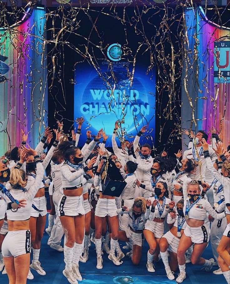 a group of cheerleaders standing on stage with their hands in the air