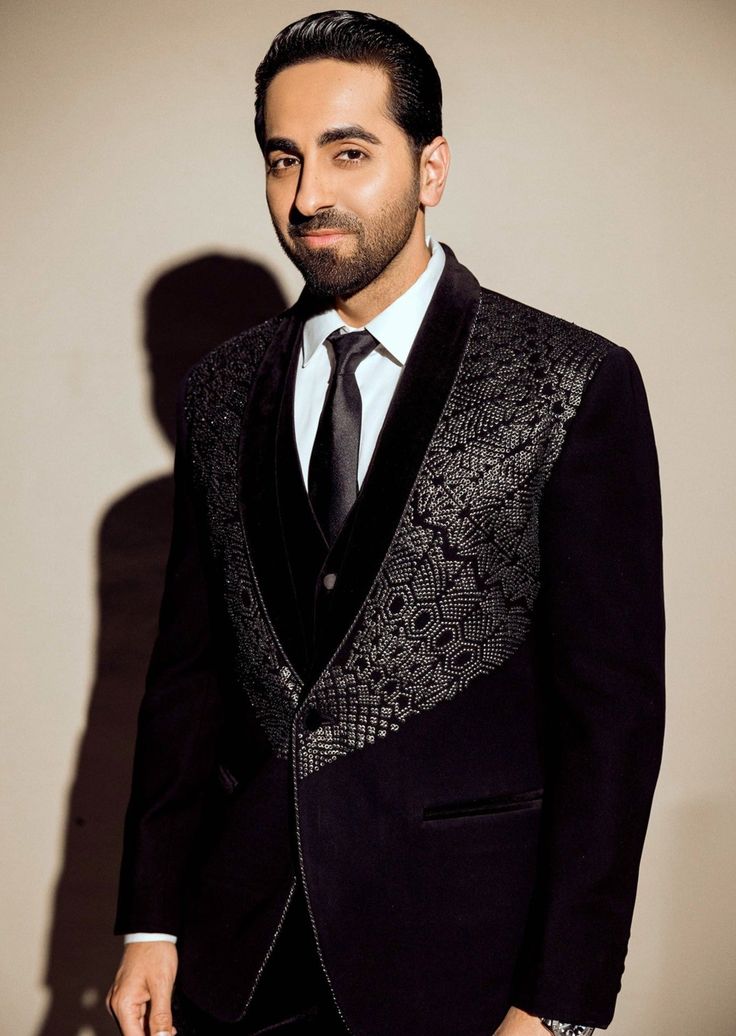 A adorned black tuxedo featuring a black velvet placket and intricate embroidery embellished with metallic beads across the chest area. Traditional Black Formal Blazer, Elegant Black Embroidered Suits, Elegant Black Suits With Intricate Embroidery, Designer Black Tuxedo For Winter, Black Festive Tuxedo Suit, Designer Black Embellished Blazer, Designer Embellished Black Blazer, Black Bandhgala With Intricate Embroidery For Formal Wear, Elegant Black Embroidered Bandhgala