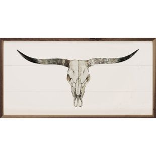 a long horn steer's skull is framed in a brown and white wood frame