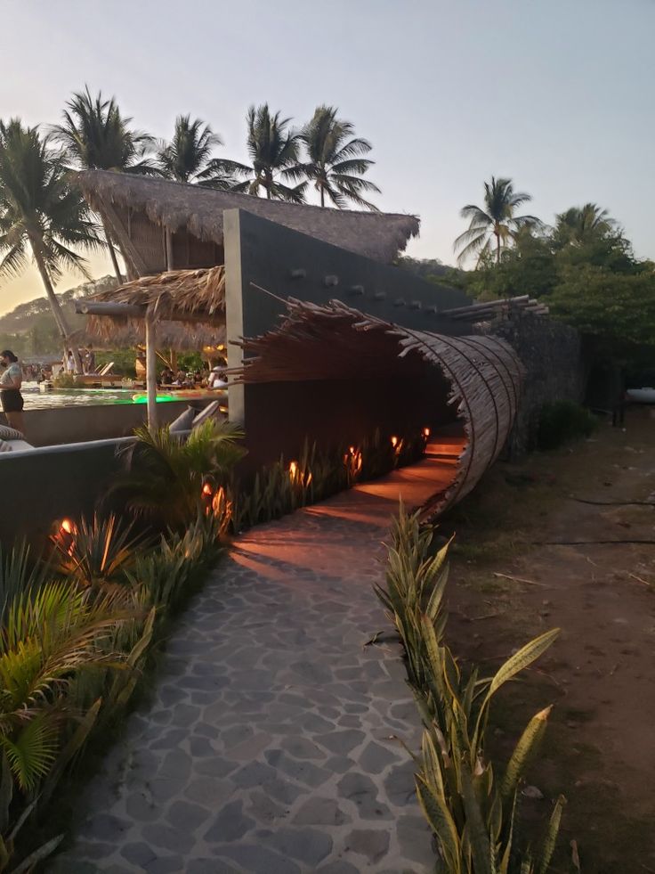 the walkway is lined with candles and palm trees in front of an overhanged pool