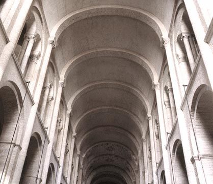 the inside of an old building with columns and arches on it's sides, looking up at the ceiling