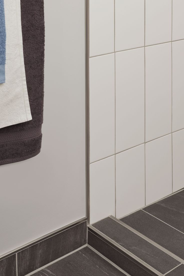 a towel hanging on the side of a shower door next to a tiled wall and floor