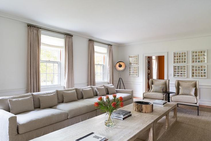 a living room with couches, chairs and a table in front of two windows