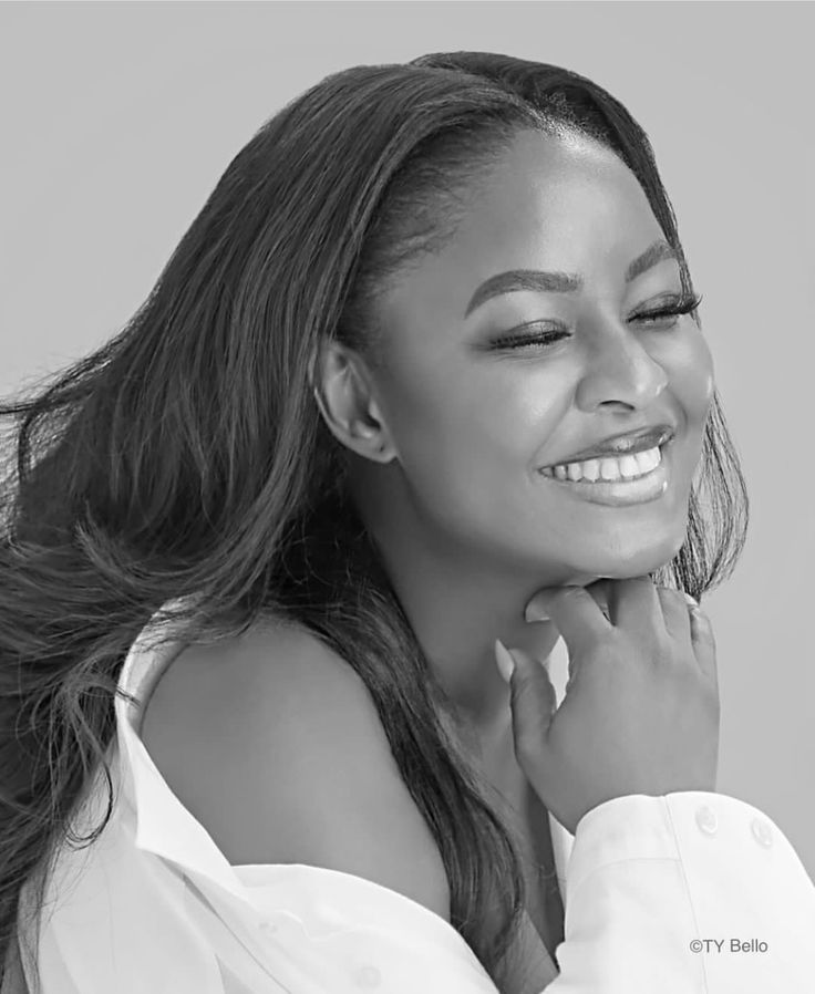 a woman with long hair smiling and looking at the camera while wearing a white shirt