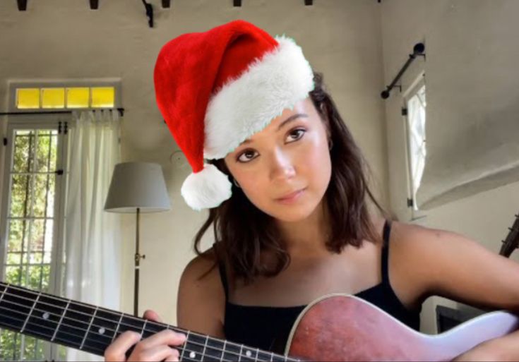 a woman wearing a santa hat playing an acoustic guitar