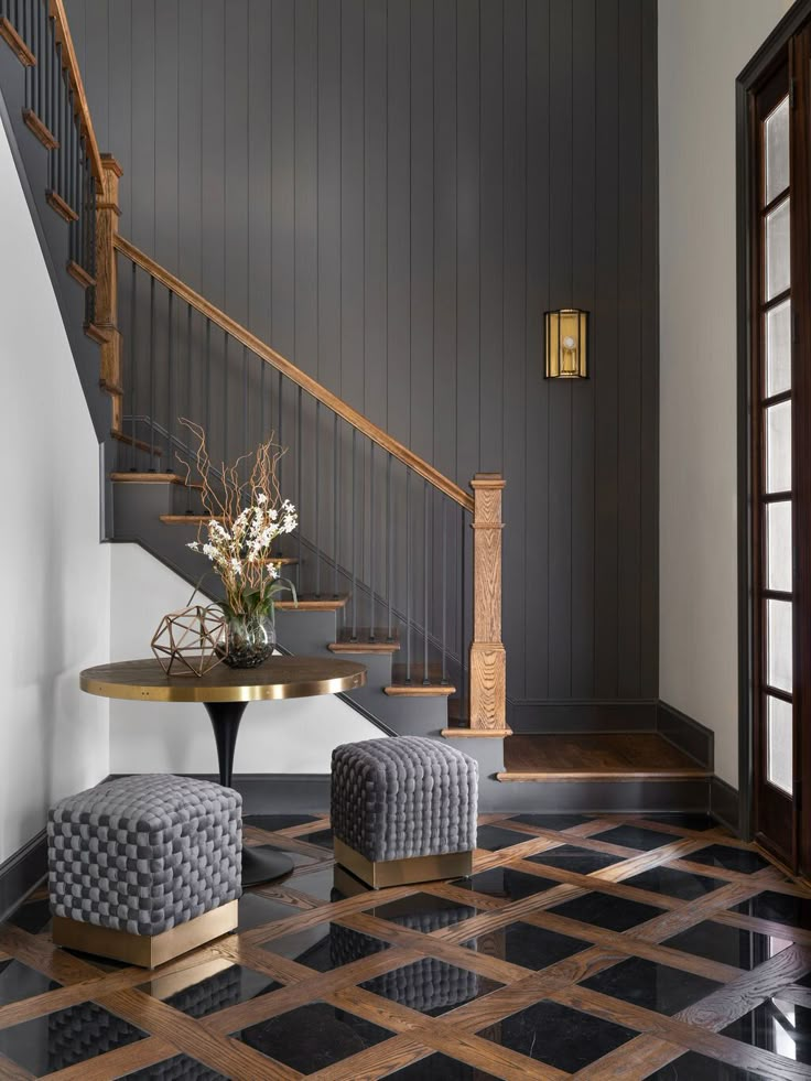 a foyer with black and white checkered flooring, two stools and a round table