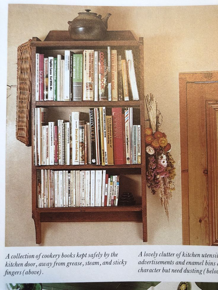 a book shelf filled with lots of books next to a vase full of flowers and fruit