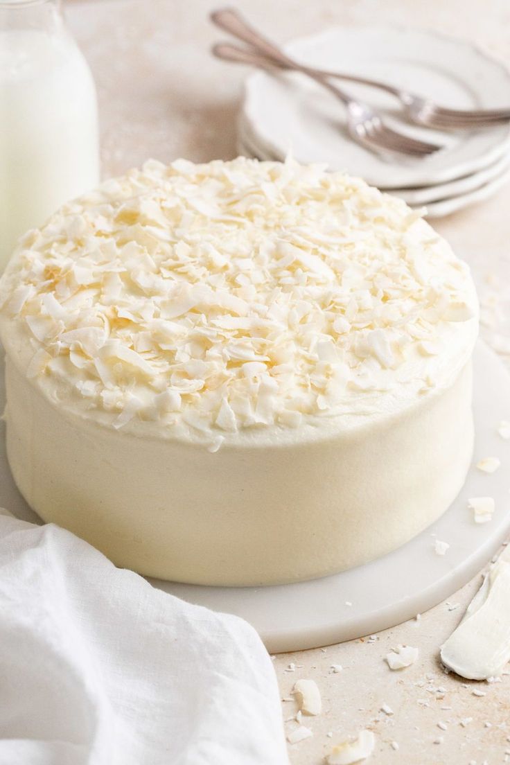 a cake with white frosting sitting on top of a plate next to a glass of milk