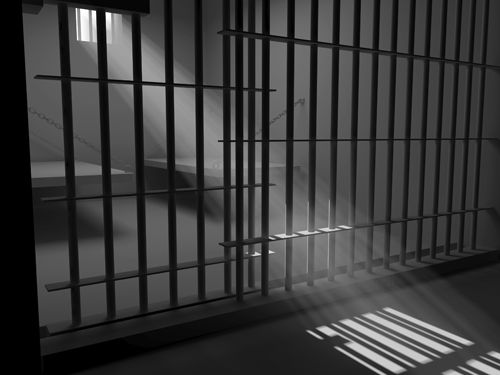 a jail cell with bars and sunlight coming through the window