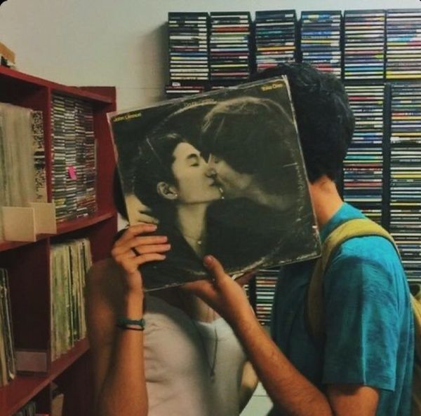 a man holding up a record in front of a woman's face with an album on it