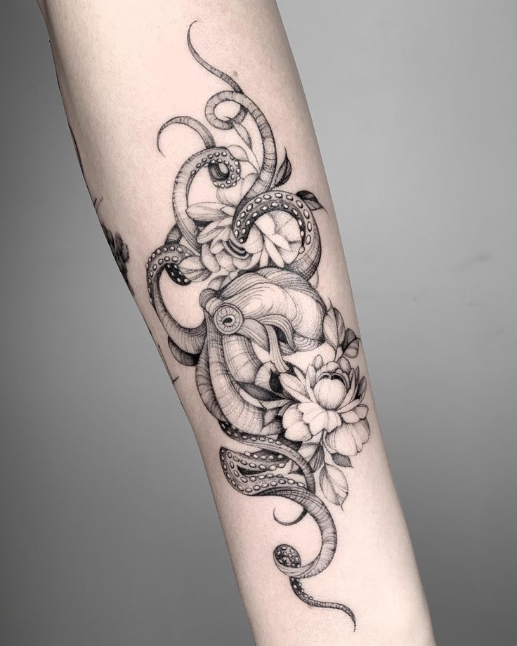 a woman's leg with an octopus and flowers tattoo on the side of her arm