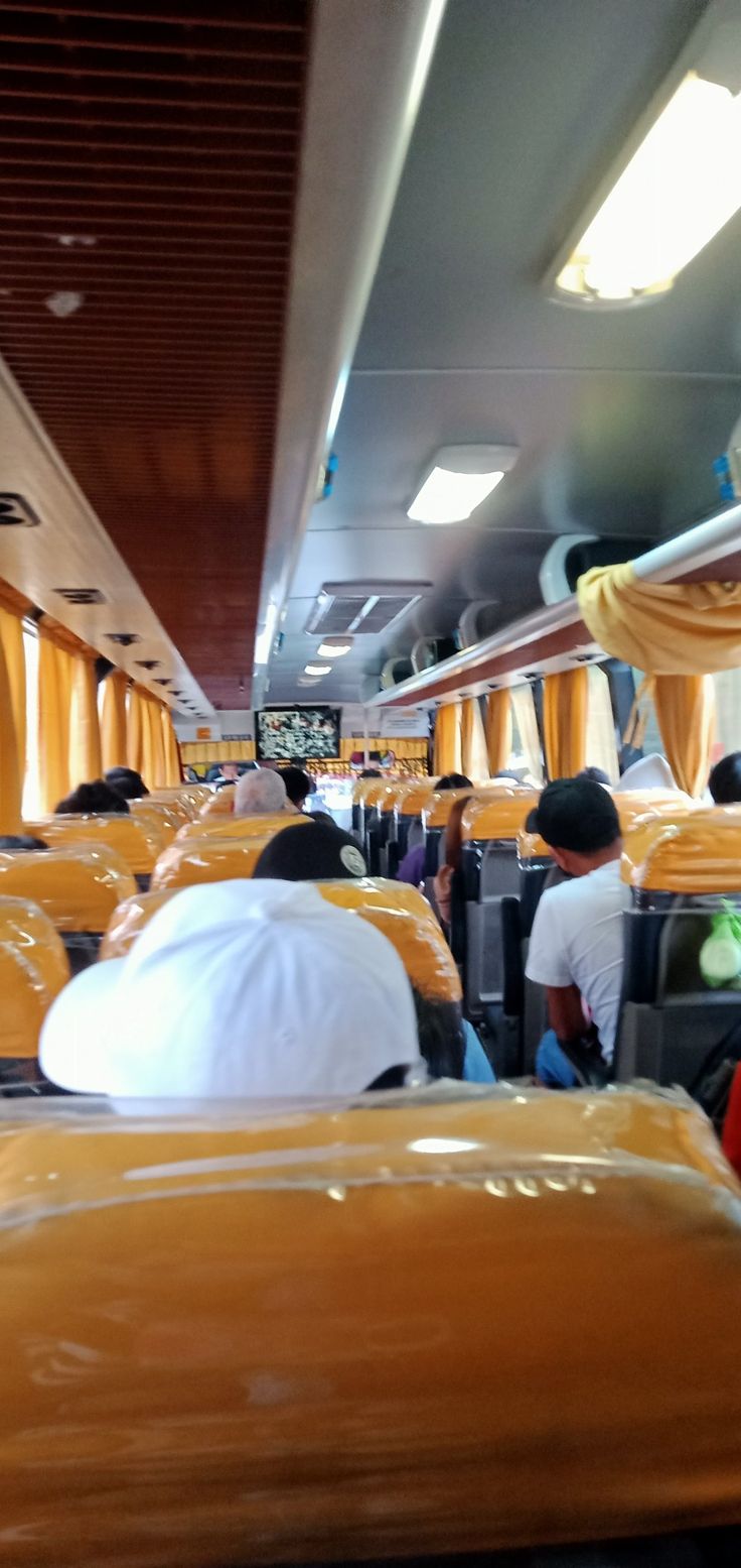 people sitting on seats in an airplane with yellow drapes hanging from the ceiling and windows