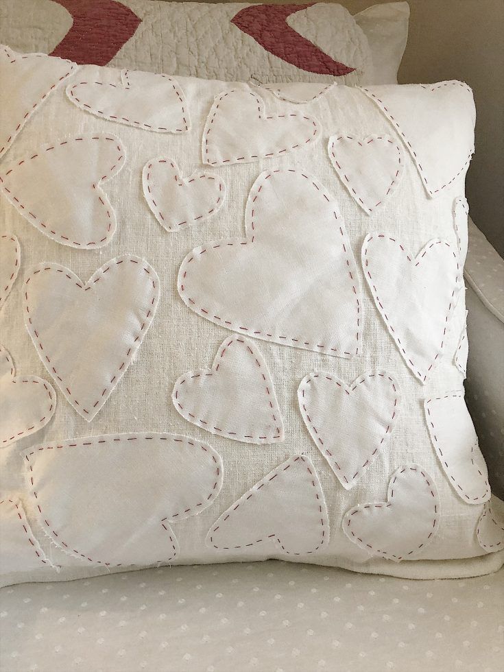 two white pillows sitting on top of a bed next to a pillow with red hearts