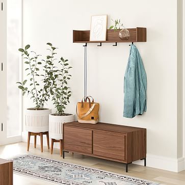 a living room with two planters and a coat rack on the wall next to it