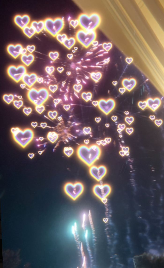 fireworks are lit up in the night sky with heart shaped lights on it's side