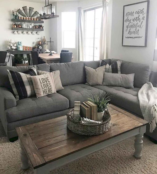 a living room with gray couches and pillows on the coffee table in front of it