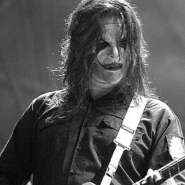 a man with long hair and makeup playing an electric guitar