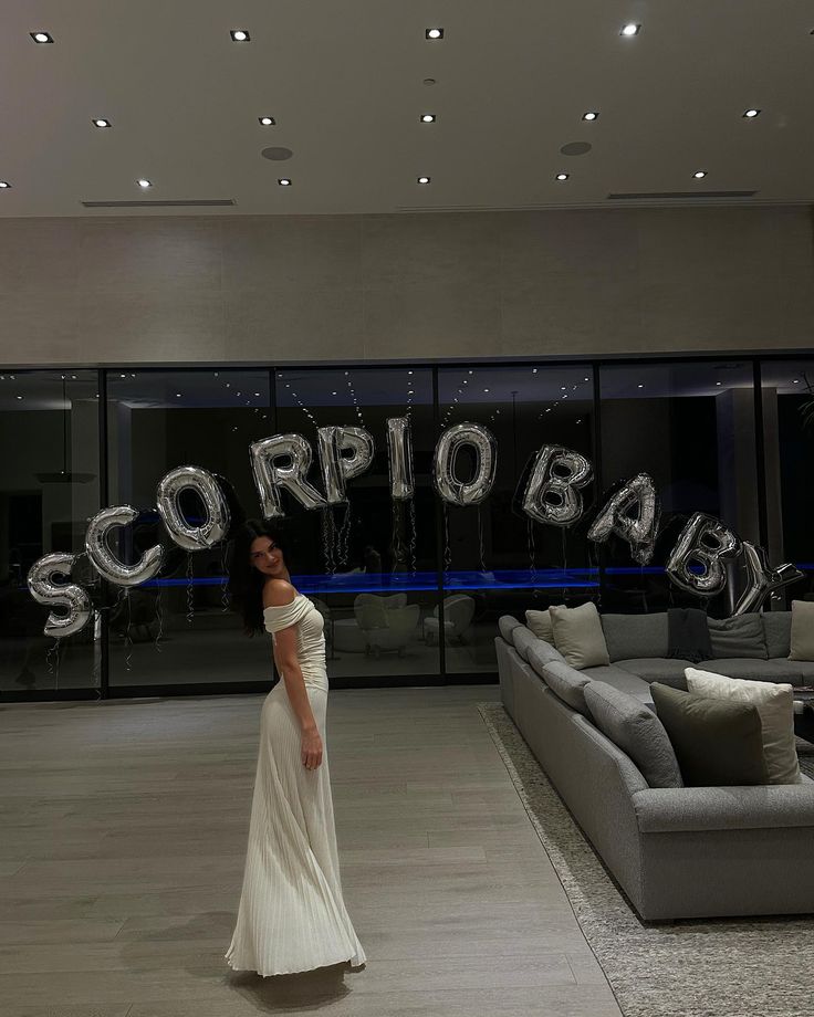 a woman standing in front of a couch with the word scorpion on it's wall