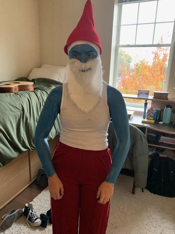 a man dressed as an elf standing in a bedroom with his hands on his hips