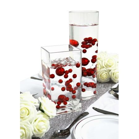 two vases with red and white flowers in them on a table set for a formal dinner