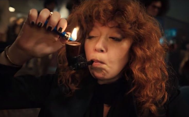 a woman with red hair holding a lighter in her hand and looking at the camera