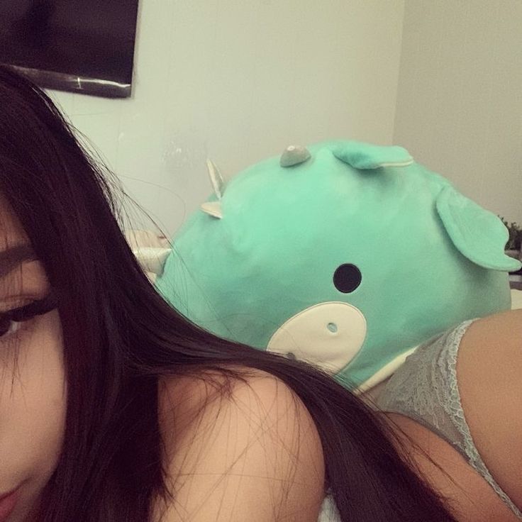 a woman laying on top of a bed next to a blue stuffed animal toy in the corner