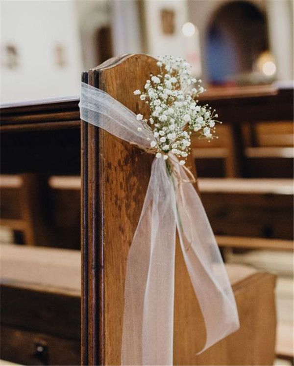 a bouquet of baby's breath sitting on top of a wooden chair in front of pews