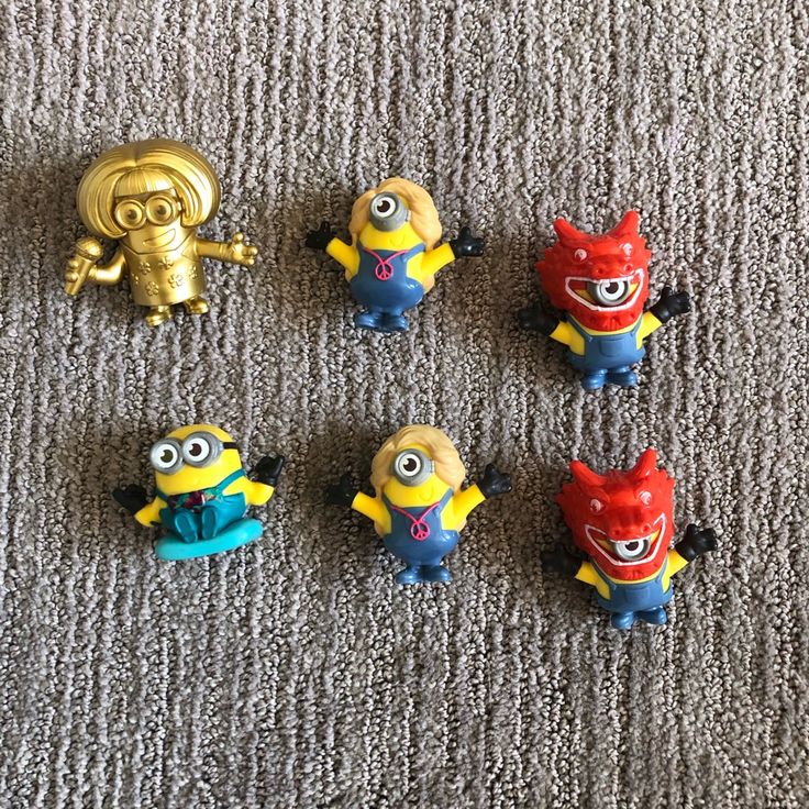 five minion toys are sitting on the carpet next to each other and one has a gold figurine