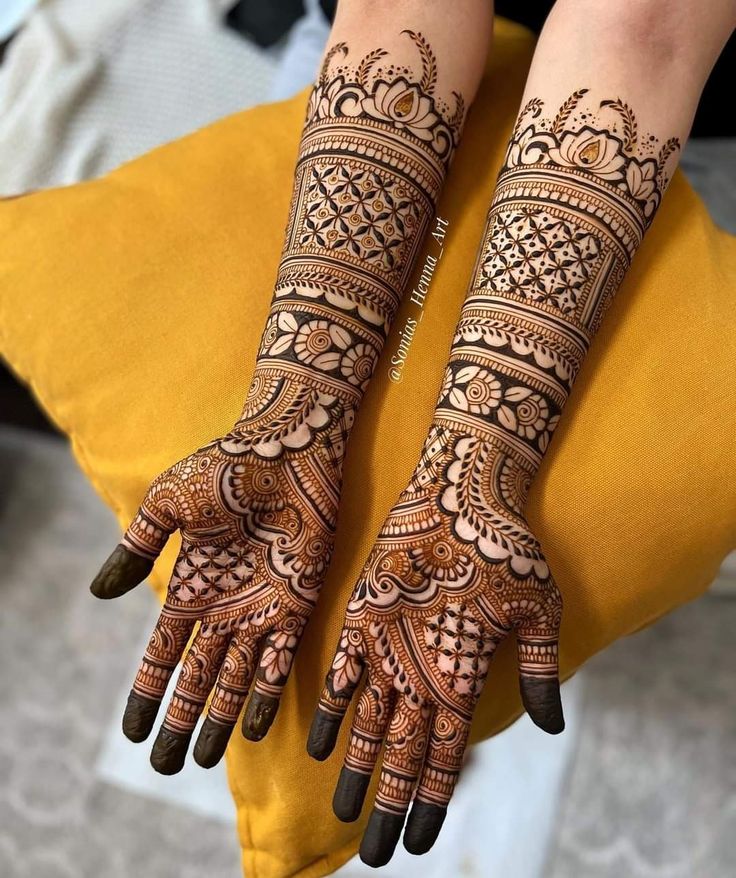 two hands with henna tattoos on them, one is showing the intricate pattern and the other