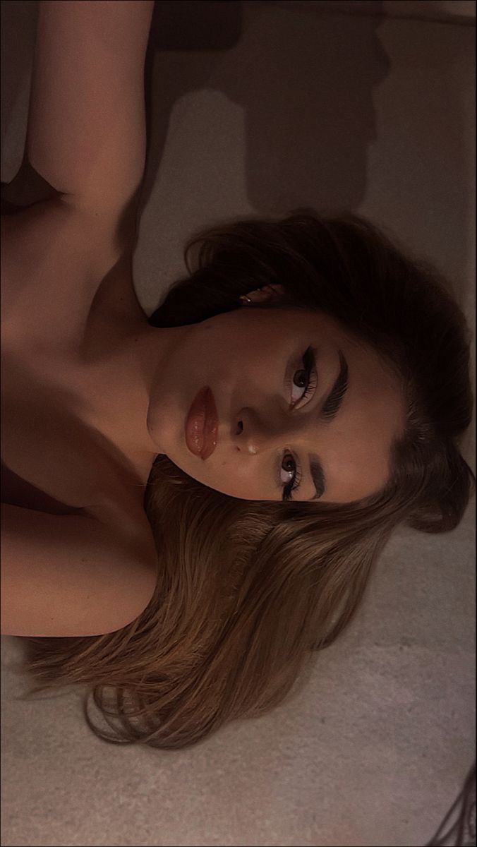 a naked woman laying on the floor with her hair blowing in the wind and looking at the camera