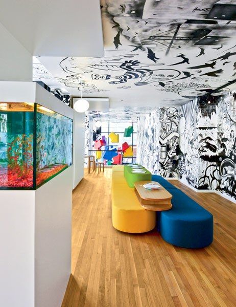 an aquarium in the middle of a room with colorful furniture and wallpaper on the walls