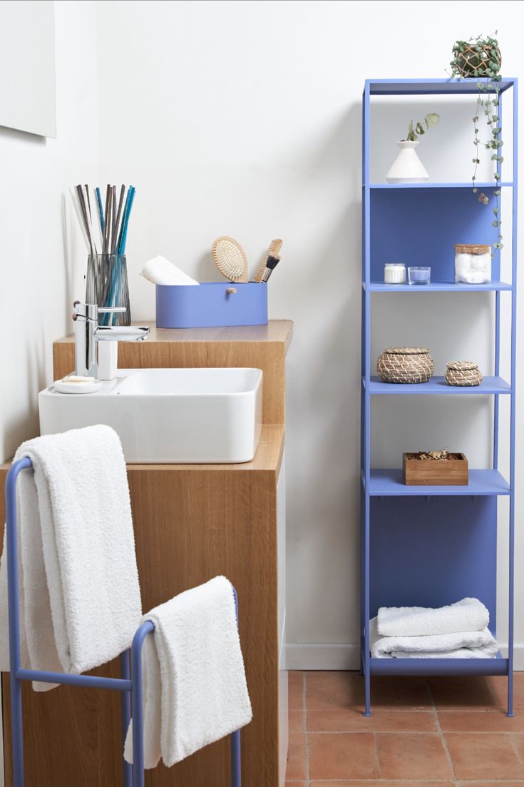 a blue shelf next to a white sink in a room with tile floors and walls