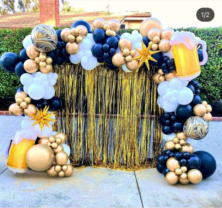 an arch made out of balloons and streamers with gold, black and white decorations