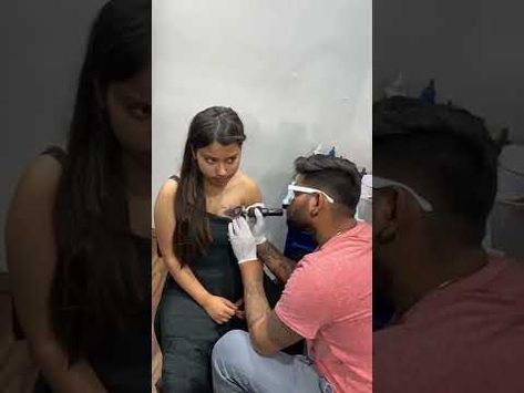 a woman getting her teeth checked by a man in a pink shirt and white gloves