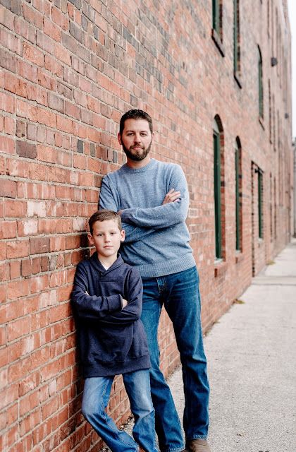 a man and boy leaning against a brick wall