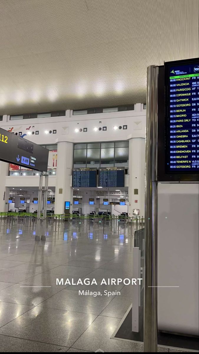 an airport terminal with many electronic signs