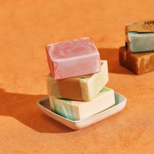 three soap bars stacked on top of each other in small dishes, one pink and one green