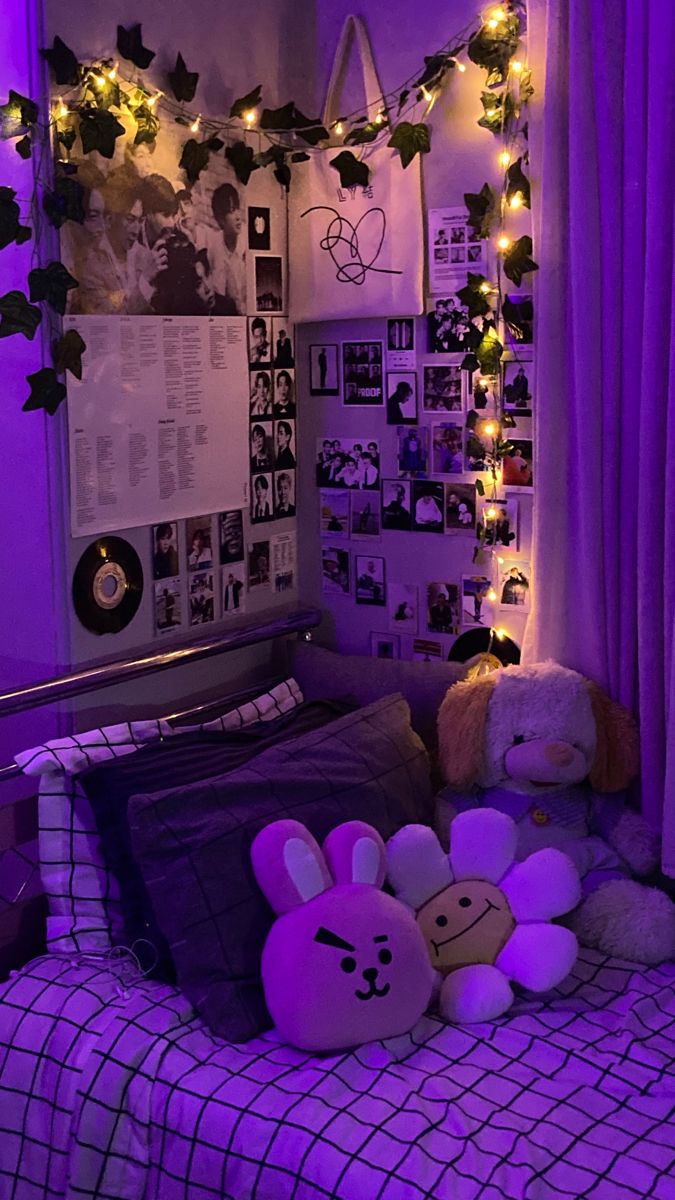 some stuffed animals on a bed in a room with purple lights and pictures above it