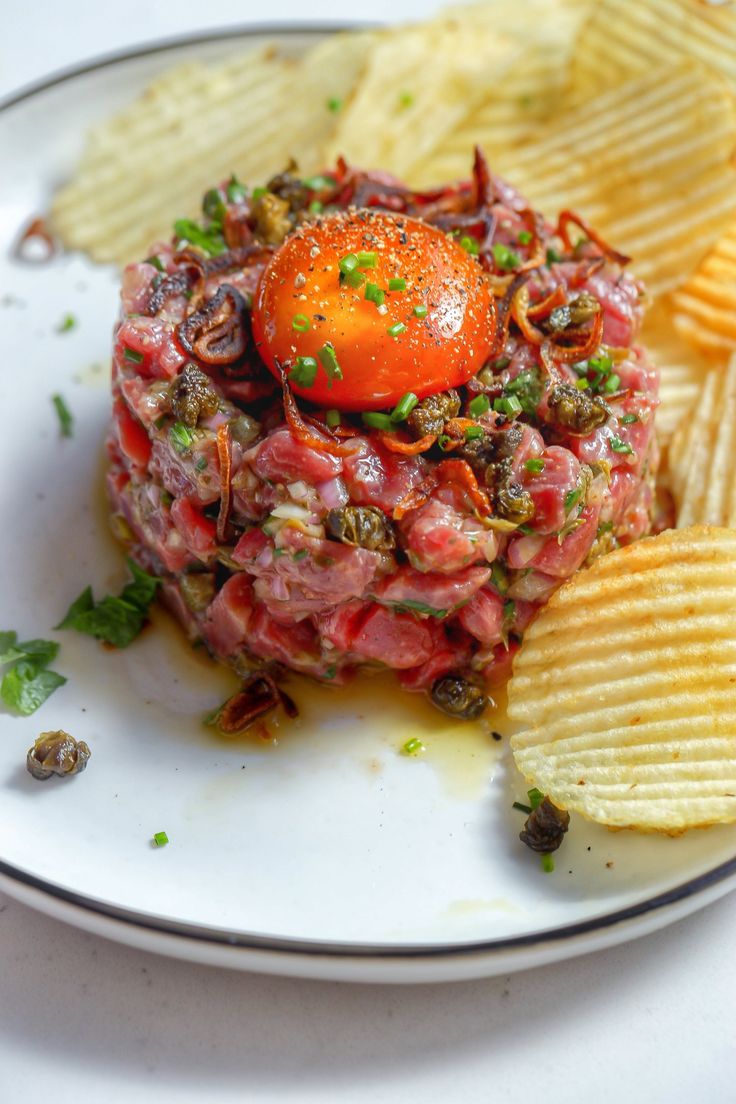 a white plate topped with potato chips and a tomato