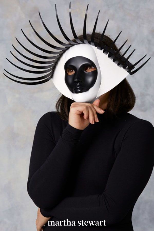 a woman wearing a black and white mask with long eyelashes on her head, covering her face