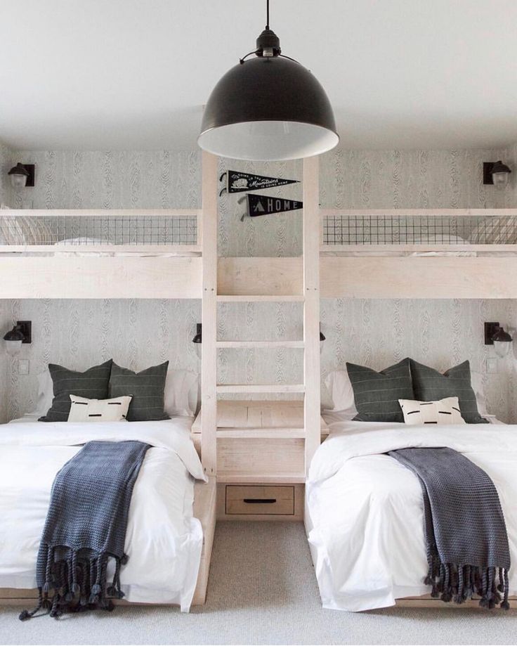 two bunk beds with white sheets and black pillows