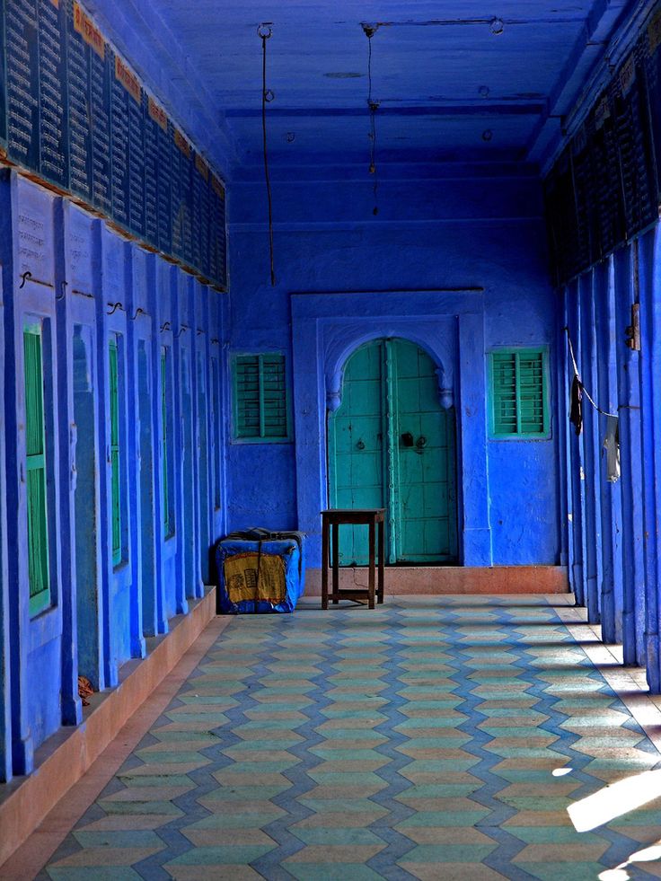 an empty hallway with bright blue walls and green shutters on the doors is shown